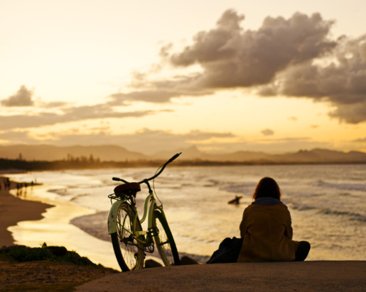 Person next to bike enjoy sunset at the beach